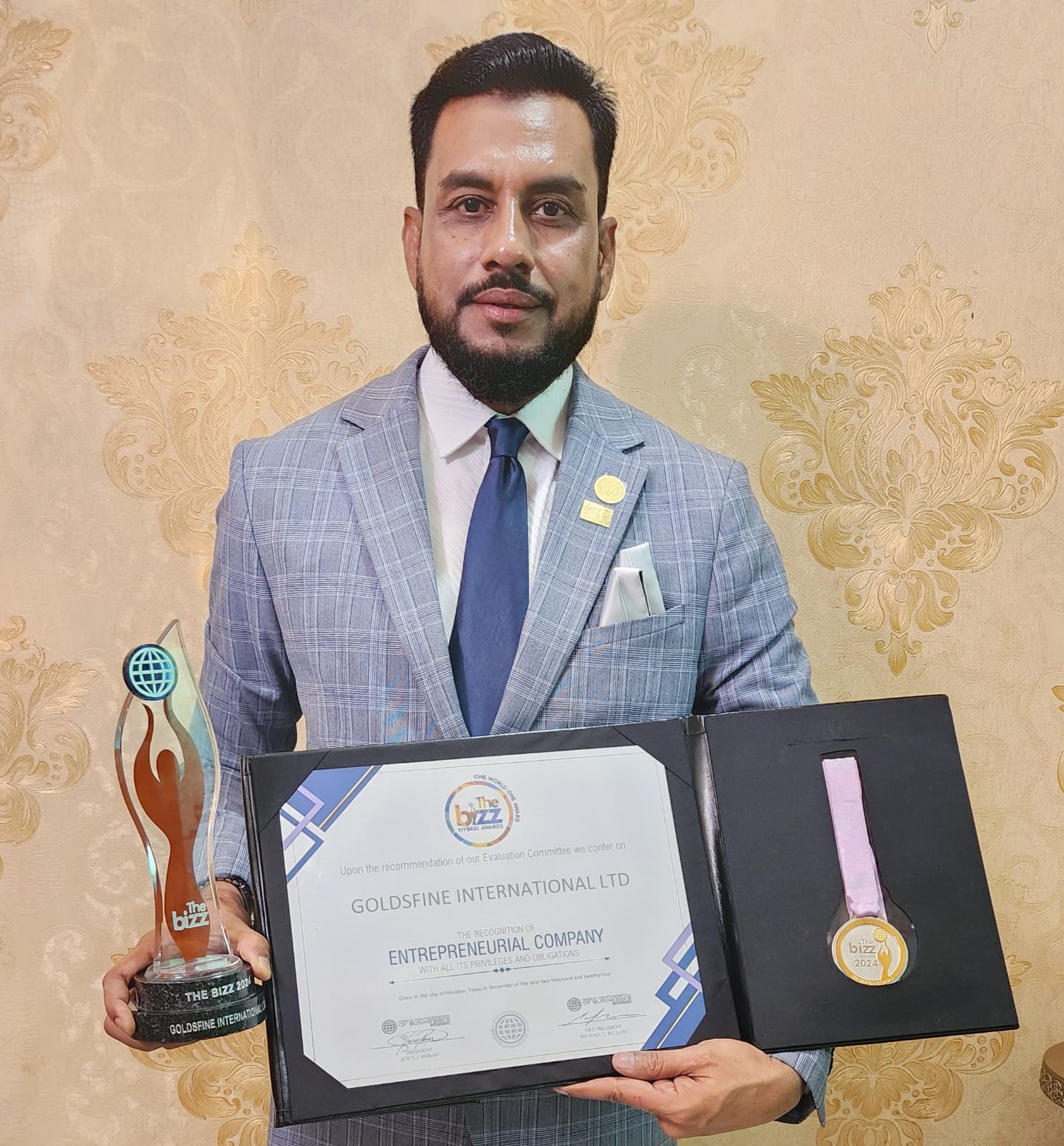 The Bizz 2024 Award - Goldsfine International Ltd. recipient holding trophy, certificate, and medal